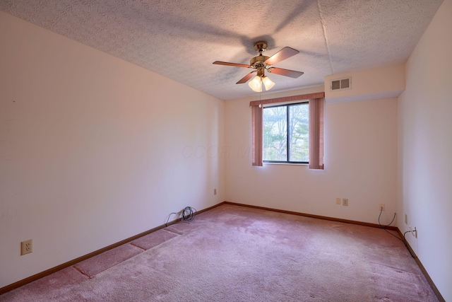 spare room with light colored carpet, visible vents, ceiling fan, and baseboards