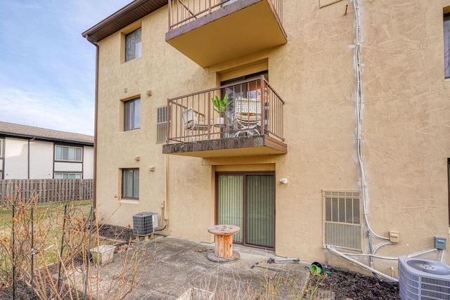 rear view of property with central AC, fence, a patio, and stucco siding