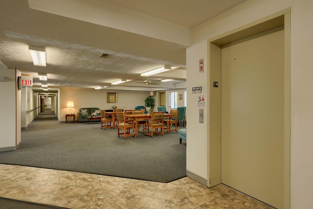 interior space featuring a textured ceiling, baseboards, and elevator