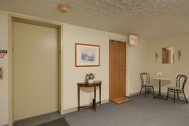 hall featuring a textured ceiling, carpet, and baseboards