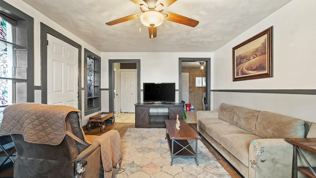 living area featuring a healthy amount of sunlight, a ceiling fan, and wood finished floors