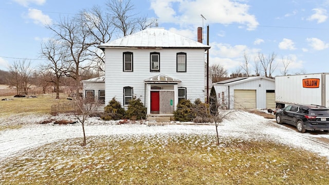 view of front of house with an outbuilding, a chimney, and a detached garage