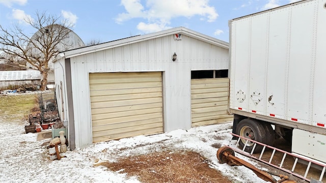 snow covered garage with a detached garage