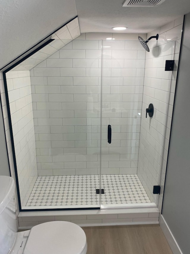 bathroom featuring baseboards, toilet, a shower stall, visible vents, and wood finished floors