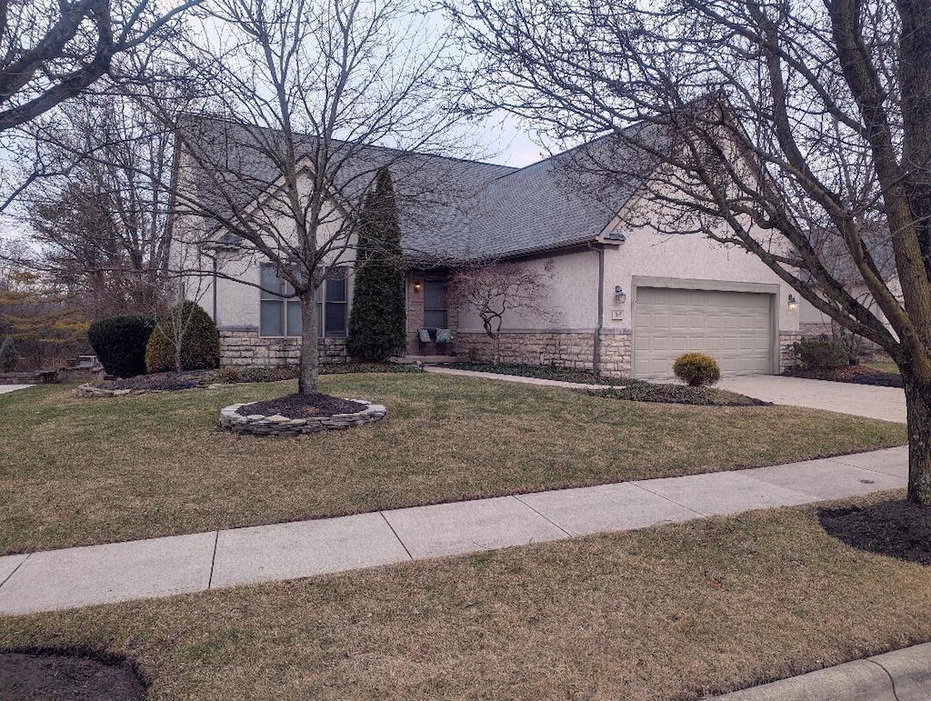 view of front of home featuring stucco siding, a front yard, a garage, stone siding, and driveway