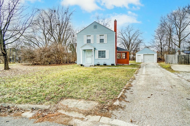 traditional-style house with an outbuilding, a chimney, a front yard, fence, and driveway