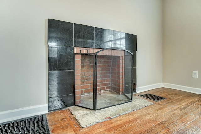 interior space with a fireplace, wood finished floors, visible vents, and baseboards