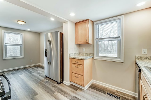 kitchen featuring light wood finished floors, stainless steel fridge, light brown cabinets, and visible vents