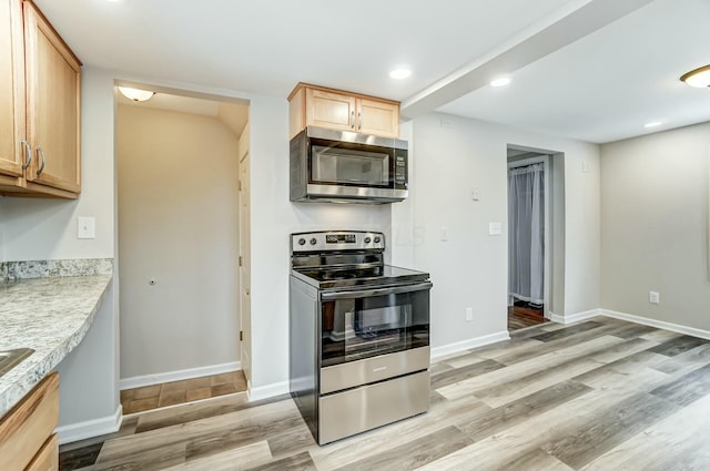 kitchen featuring light wood finished floors, light countertops, appliances with stainless steel finishes, and baseboards