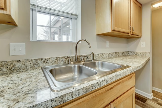 kitchen featuring light countertops, a sink, baseboards, and wood finished floors