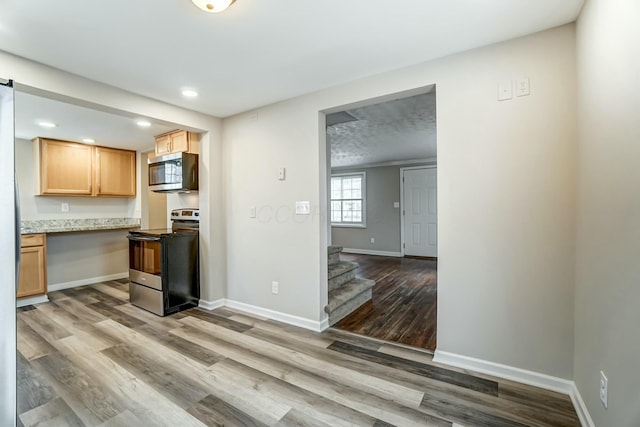 kitchen featuring baseboards, wood finished floors, light stone countertops, stainless steel appliances, and recessed lighting