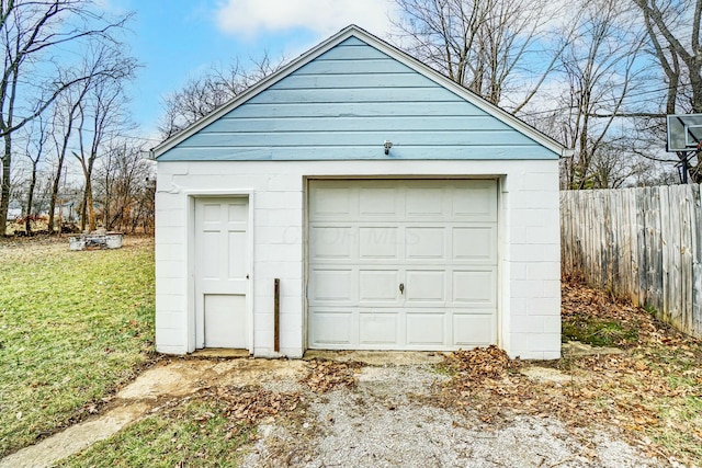 detached garage featuring fence and driveway