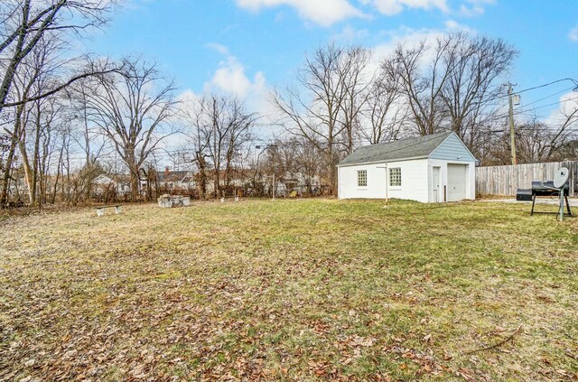 view of yard featuring a detached garage, fence, and an outbuilding