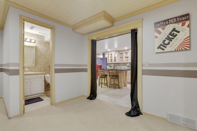 corridor featuring visible vents, ornamental molding, light carpet, a sink, and baseboards