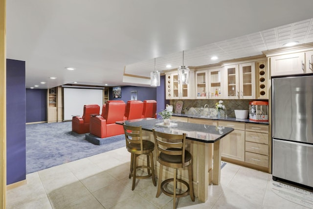 kitchen featuring a breakfast bar area, a kitchen island, backsplash, freestanding refrigerator, and glass insert cabinets