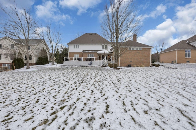 snow covered back of property with crawl space, brick siding, and a chimney