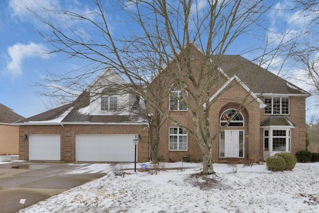 view of front facade with an attached garage, driveway, a shingled roof, and brick siding