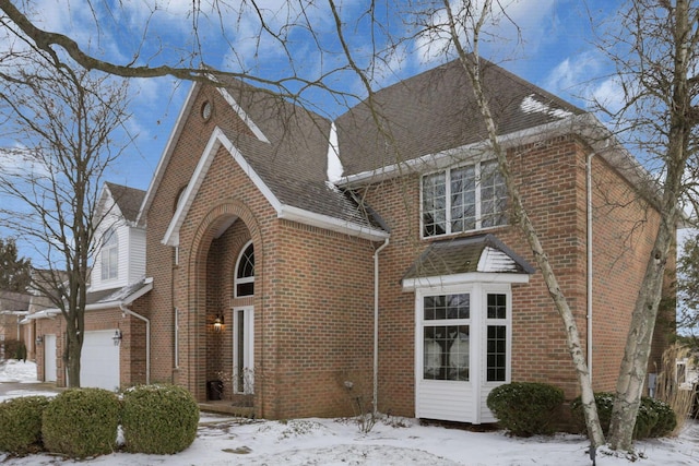 view of front facade with a shingled roof and brick siding