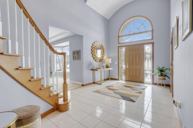 tiled entryway with high vaulted ceiling and baseboards