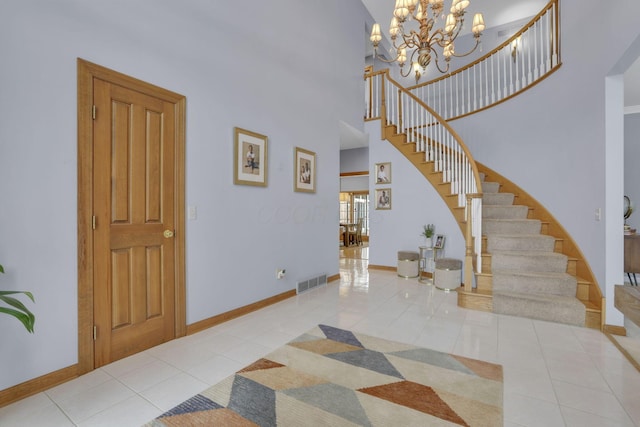 foyer with a high ceiling, visible vents, baseboards, stairway, and tile patterned floors