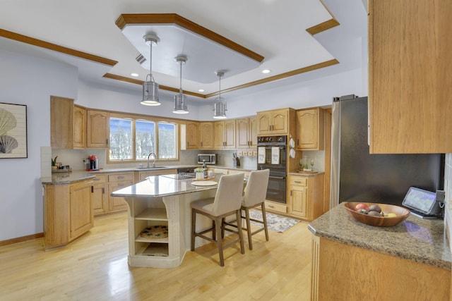 kitchen with dobule oven black, a sink, a kitchen island, decorative backsplash, and a raised ceiling