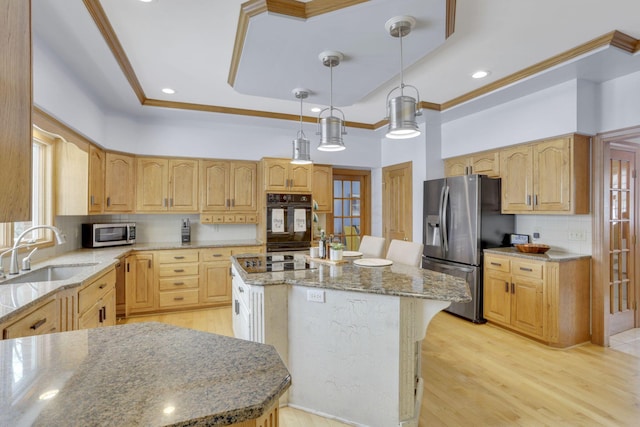 kitchen with a tray ceiling, crown molding, a kitchen island, a sink, and black appliances