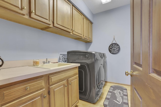 washroom featuring cabinet space, baseboards, washer and clothes dryer, and a sink