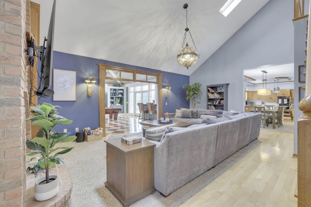 living area with light wood-style flooring, high vaulted ceiling, and a chandelier