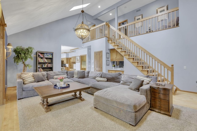 living area featuring baseboards, stairway, wood finished floors, an inviting chandelier, and high vaulted ceiling