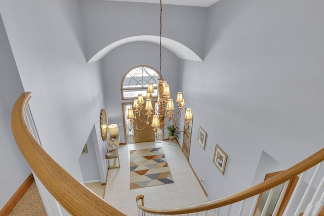 foyer with light tile patterned floors, a high ceiling, baseboards, stairway, and an inviting chandelier