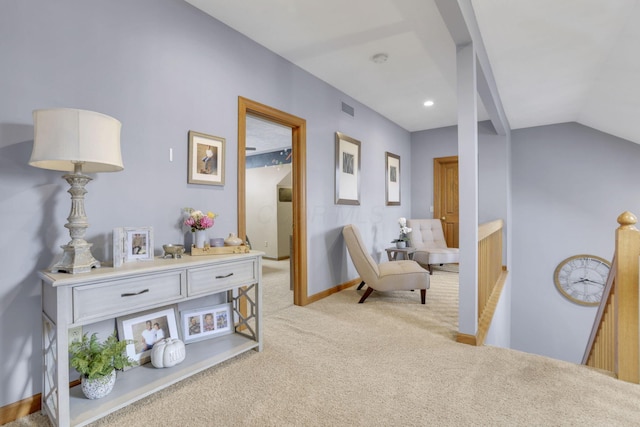 living area featuring visible vents, baseboards, lofted ceiling, an upstairs landing, and carpet floors