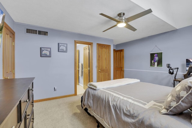 bedroom with light carpet, a ceiling fan, visible vents, baseboards, and ensuite bath