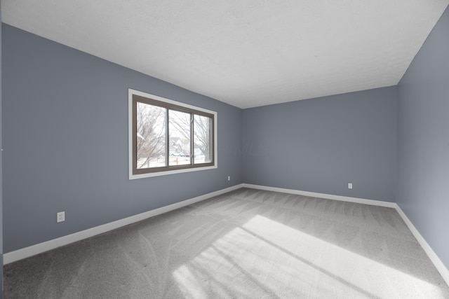 carpeted empty room featuring baseboards