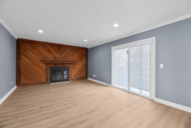 unfurnished living room with baseboards, wood walls, and light wood finished floors