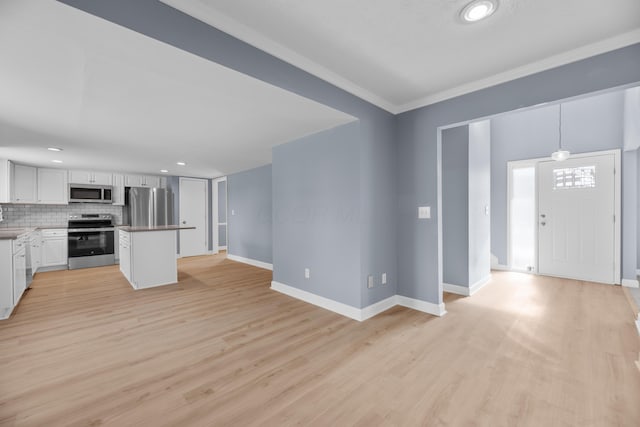 kitchen featuring light wood-type flooring, white cabinetry, appliances with stainless steel finishes, decorative backsplash, and baseboards