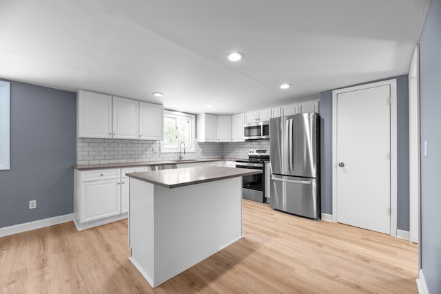 kitchen featuring baseboards, light wood-style flooring, white cabinets, appliances with stainless steel finishes, and backsplash