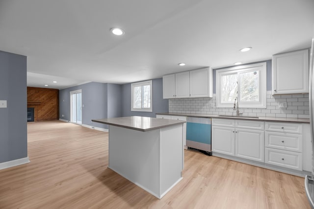 kitchen with dishwashing machine, light wood-style flooring, decorative backsplash, and a sink