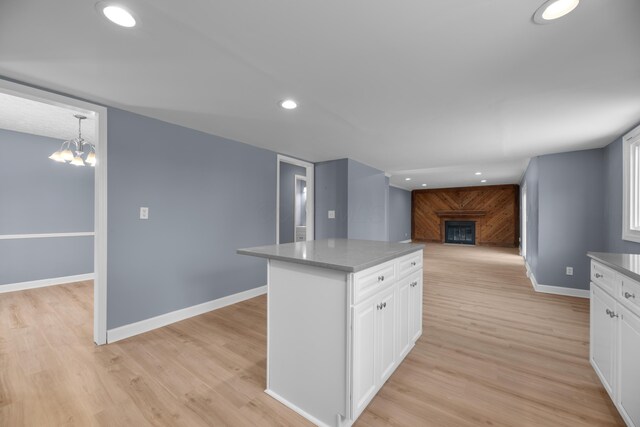 kitchen featuring baseboards, white cabinetry, a fireplace, and light wood finished floors