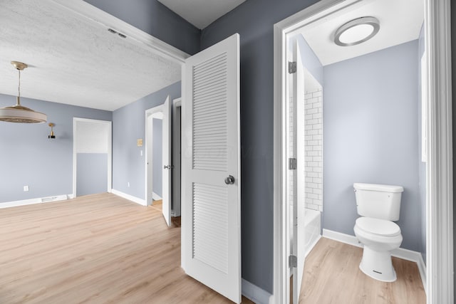 bathroom with visible vents, toilet, a textured ceiling, wood finished floors, and baseboards