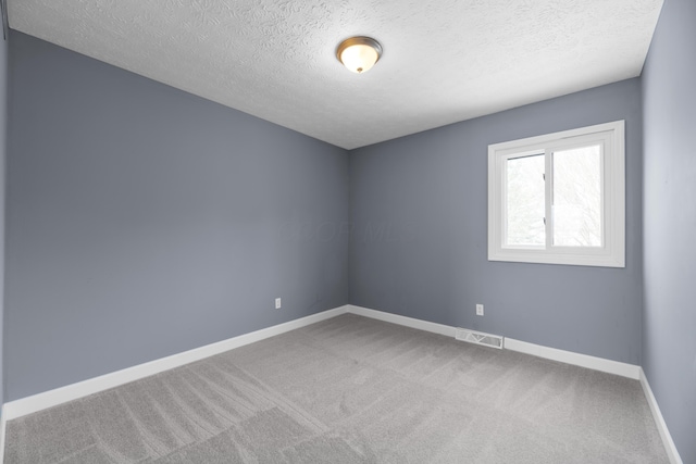 unfurnished room with visible vents, a textured ceiling, baseboards, and carpet