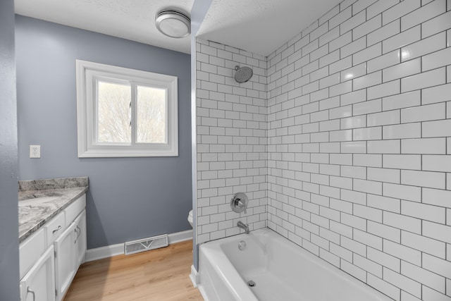 bathroom featuring visible vents, baseboards, toilet, wood finished floors, and vanity