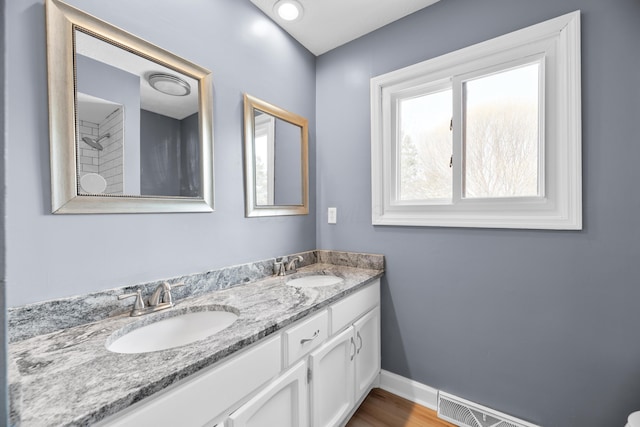 full bath featuring double vanity, visible vents, baseboards, and a sink