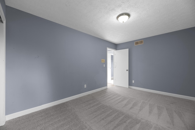 carpeted empty room featuring baseboards, visible vents, and a textured ceiling