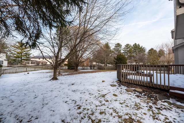 yard covered in snow with a wooden deck and fence