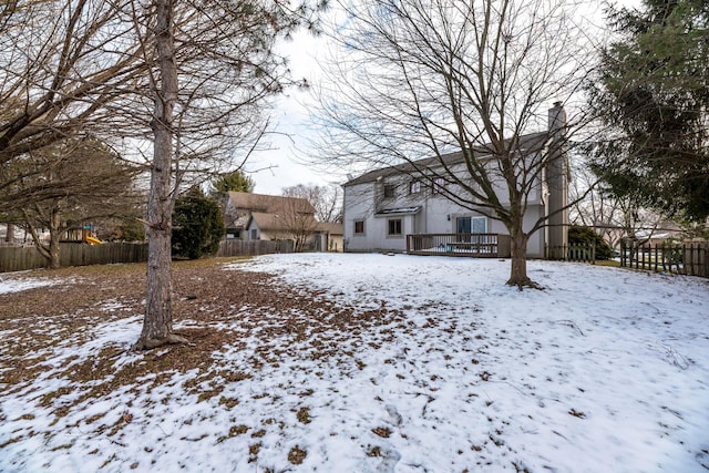 yard layered in snow with a wooden deck and fence