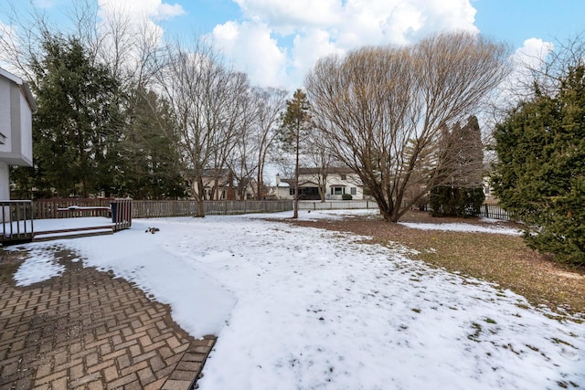 snowy yard featuring fence and a wooden deck