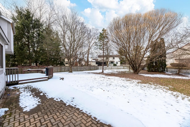 yard covered in snow with a deck and fence