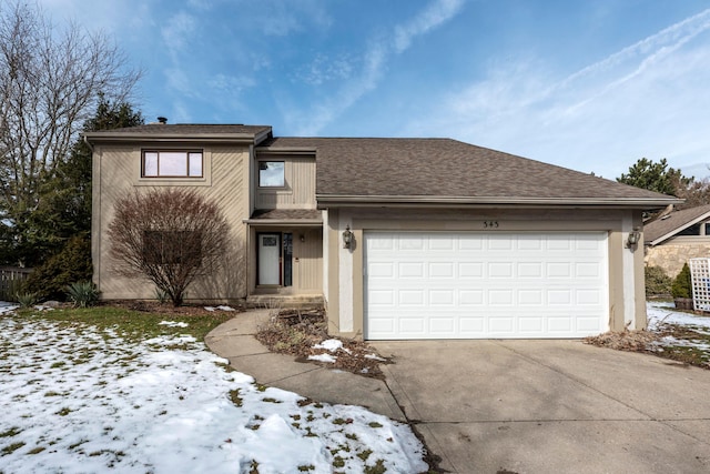 view of front of property featuring an attached garage, driveway, and a shingled roof