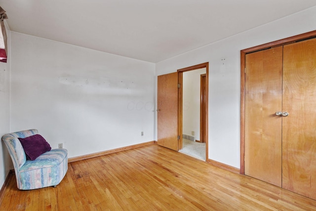 sitting room featuring baseboards, visible vents, and light wood-style floors