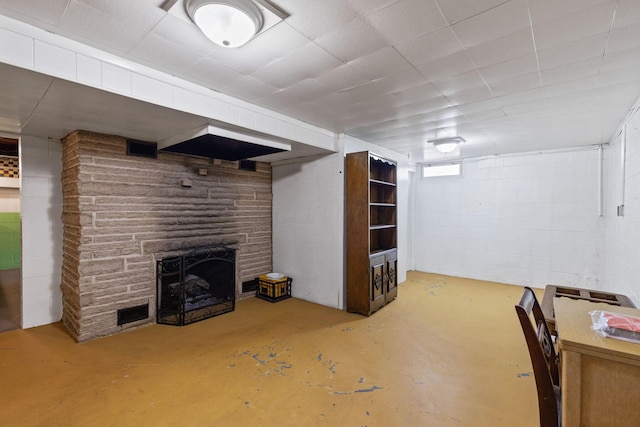 below grade area with visible vents, a fireplace, and concrete block wall